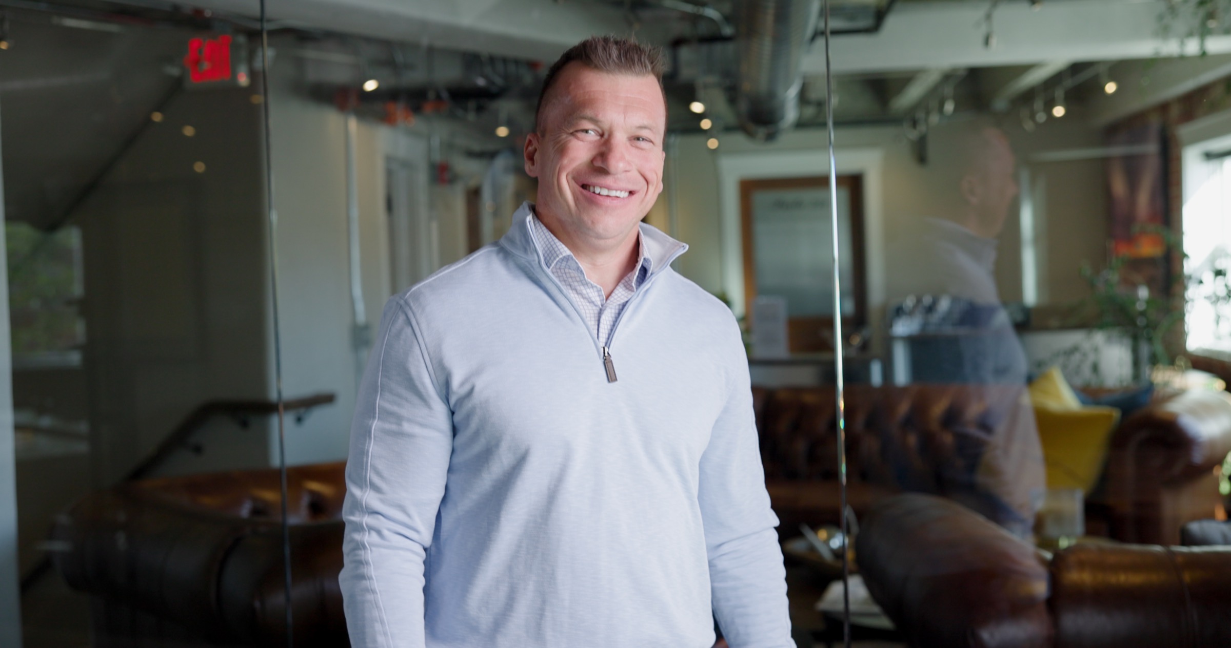 Jason Lewis in a modern office seen through glass